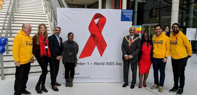 People standing either side of a red ribbon sign in an office building