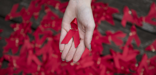One hand holding one red ribbon
