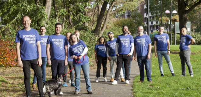 Large group of Ribbon Walk people in THT shirts in park with dog
