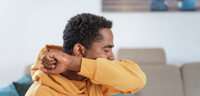 Man coughing into arm