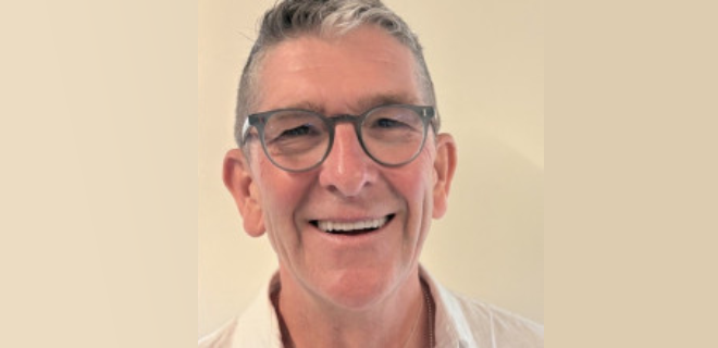 Niall Bolger, a white man with grey hair and grey round-rimmed glasses, smiling.