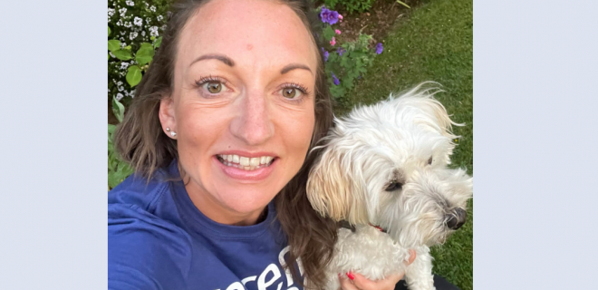 Sarah Ashford smiling at camera and holding a small white dog