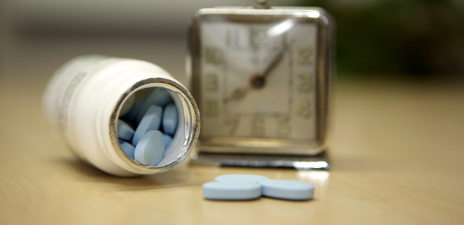 Blue pills next to an alarm clock