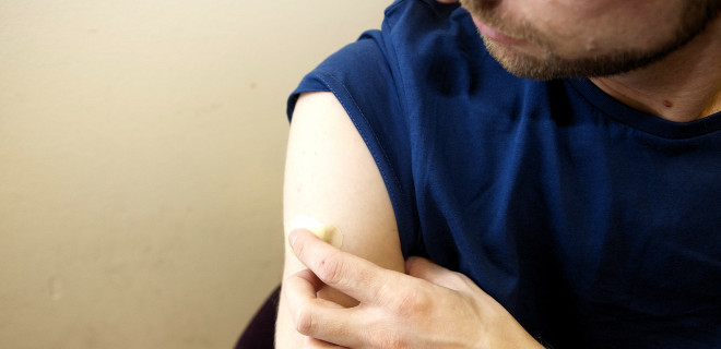 Man holding plaster on his arm after an injection