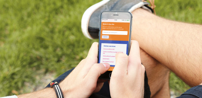 Someone using Terrence Higgins Trust's website on their iphone in a park