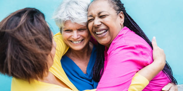 Group of three older adults hugging and laughing