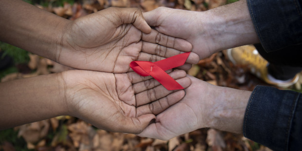 Red ribbon held by four hands