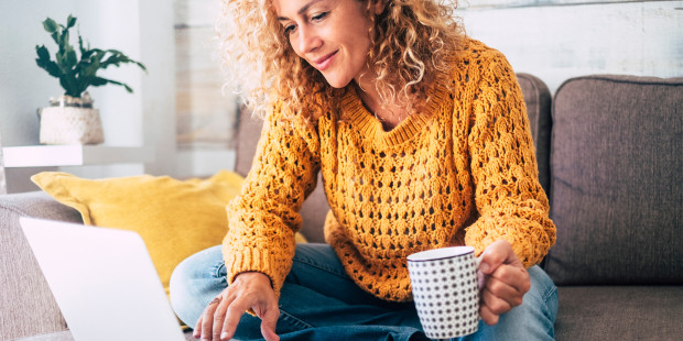 Woman with a hot drink using a laptop