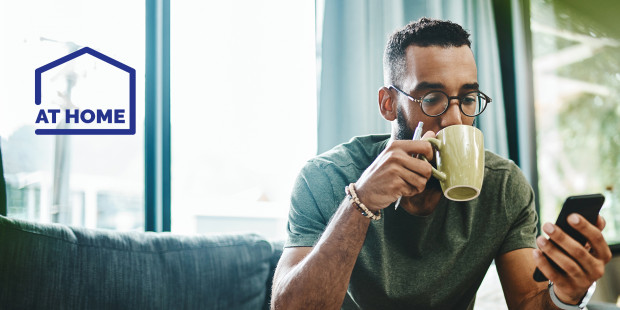 Man relaxing with his phone and a hot drink - At Home
