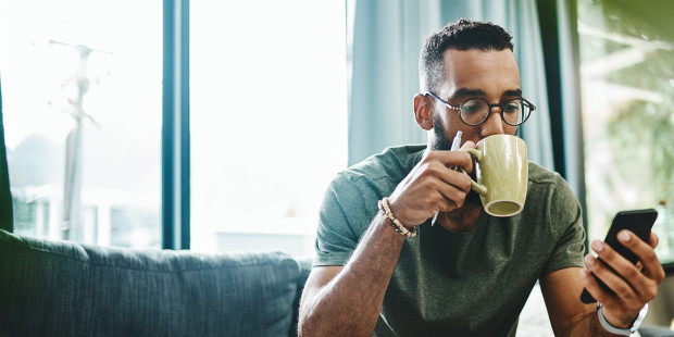 Man sipping a drink and looking at his phone