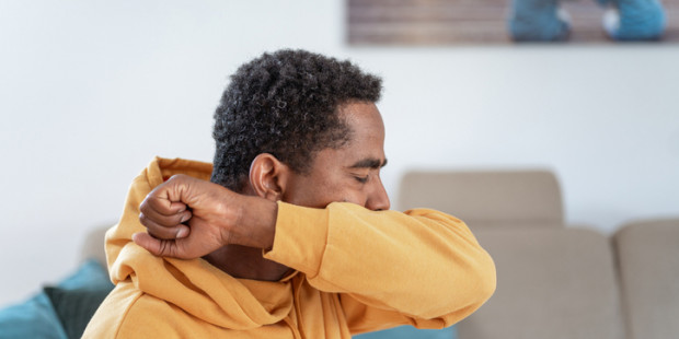Man coughing into arm Man coughing into arm