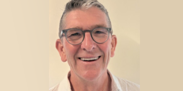 Niall Bolger, a white man with grey hair and grey round-rimmed glasses, smiling.
