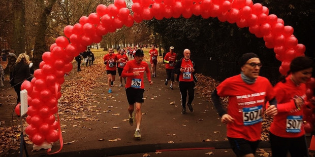 Red Run runners in Victoria Park, running through balloon archway