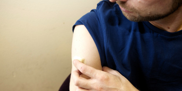 Man holding plaster on his arm after an injection