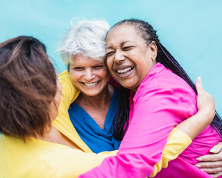 Group of three older adults hugging and laughing
